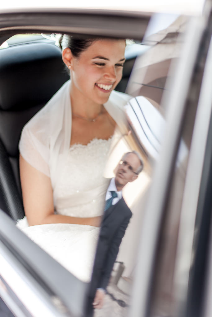 la futura sposa sorride ed attende che il padre apra lo sportello dell'auto e l'accompagni all'altare